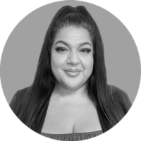 Confident Smiling Woman with Dark Hair, Professional Portrait Smiling woman with dark hair in a half-ponytail, wearing a dark top, against a gray background. Black and white.