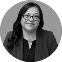 Smiling Professional Woman Black and White Portrait Smiling woman with dark wavy hair, wearing glasses, a dark blazer, and a V-neck top in a professional black and white headsh…